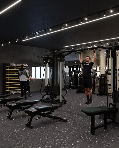 Sala pesi con trainer e iscritti tra cavi e spalliere